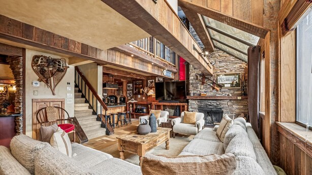Un interior rústico con chimenea de piedra, vigas de madera y una zona de estar acogedora.