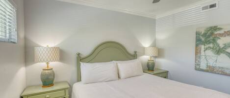 A bedroom with a bed, two nightstands, a ceiling fan, and a wall painting.