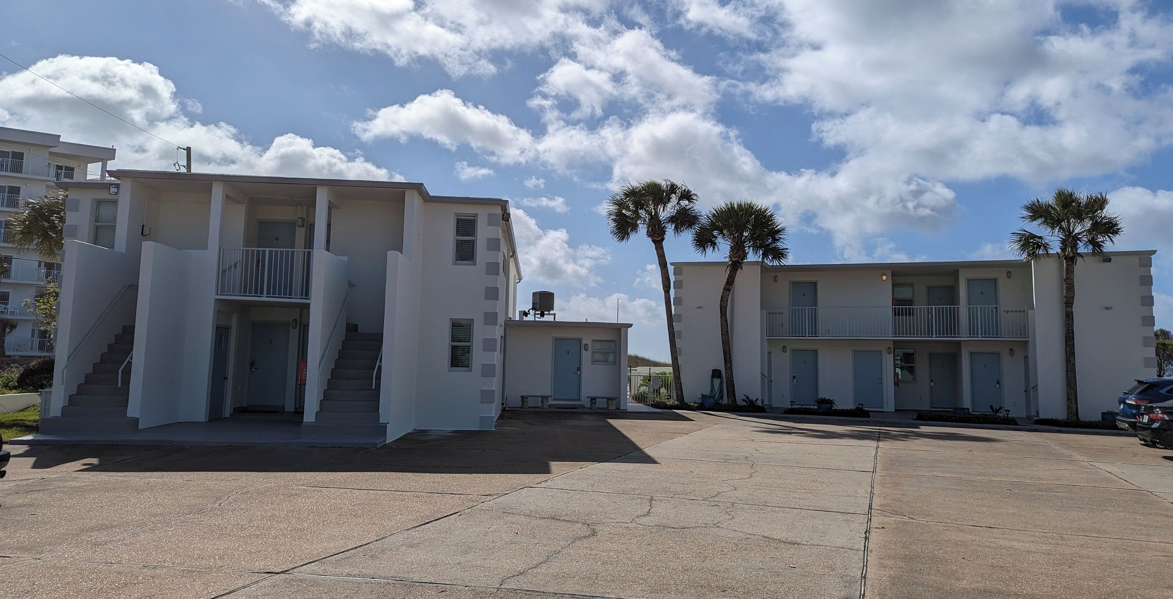 A modern building with a flat roof, multiple balconies, and a central staircase.