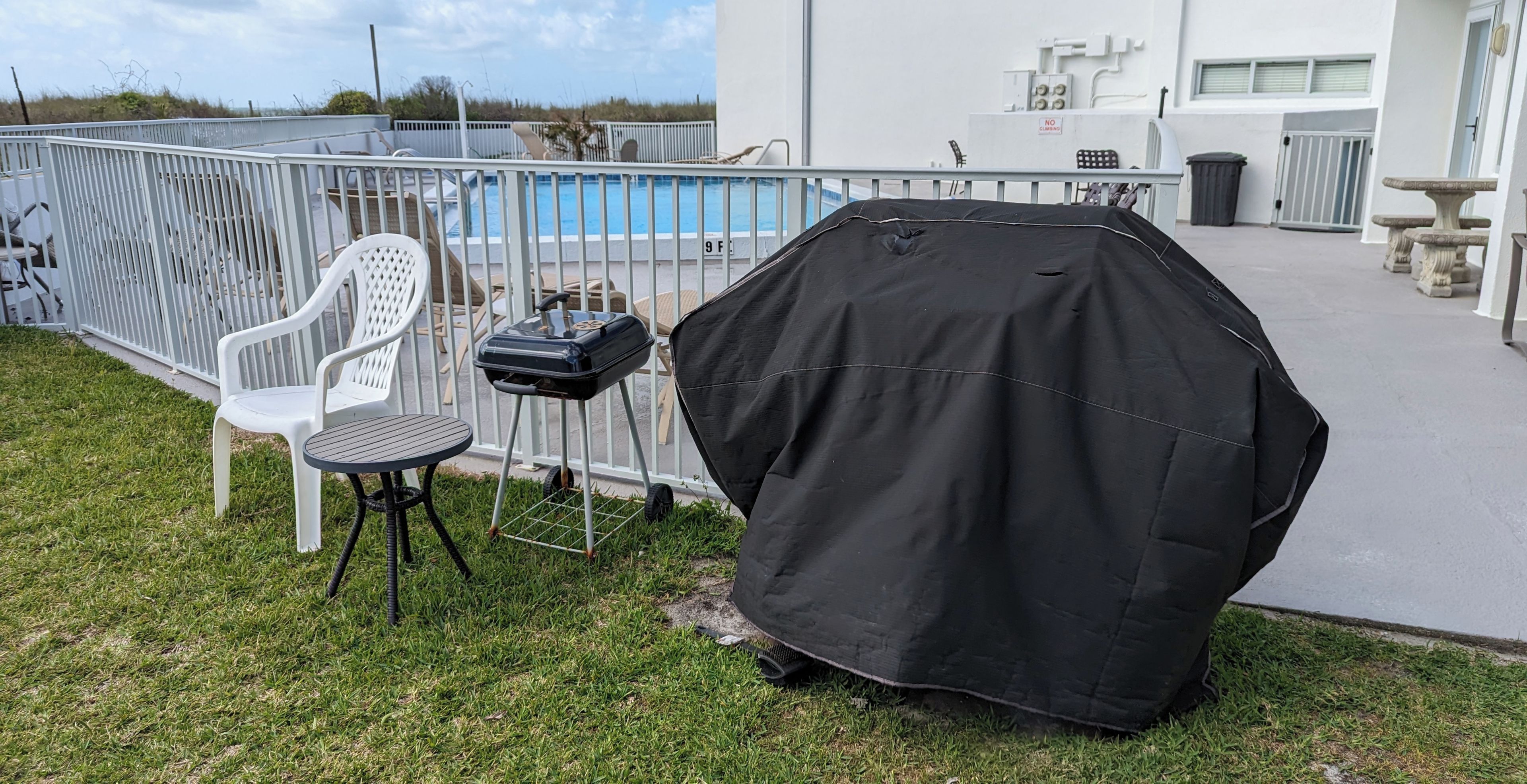 En trädgård med pool, grill och ett överbyggt grillområde.