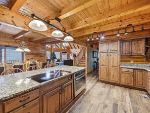 A spacious kitchen with granite countertops, wooden cabinets, and a central island. - Cabin w/Amazing Views, Large Game Room, Hot Tub (Sevierville)