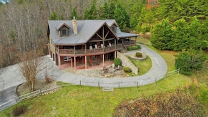 A large, two-story log cabin with a wrap-around porch and a stone fireplace. - Cabin w/Amazing Views, Large Game Room, Hot Tub (Sevierville)