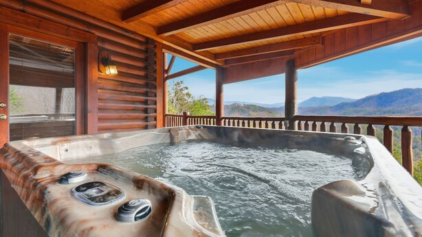 A wooden cabin with a hot tub and a view of the mountains. - Cabin w/Amazing Views, Large Game Room, Hot Tub (Sevierville)