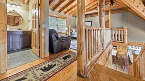 A wooden interior with a kitchen, a seating area, and a staircase. - Cabin w/Amazing Views, Large Game Room, Hot Tub (Sevierville)