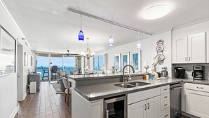 A modern kitchen with a large island, stainless steel appliances, and a view to the outside.