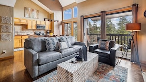 A spacious living room with a grey sofa, a coffee table, and a balcony with a view of the outdoors. - 4 O'Clock A16: Ski-In Condo, Gas Fireplace, 1 Block to Snowflake Lift. (Breckenridge)