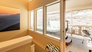 Ein Zimmer mit großem Fenster, Whirlpool und einer Terrasse mit Stuhl.