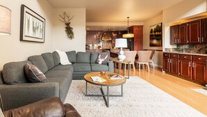 Ein modernes Wohnzimmer mit einer Eckcouch, einem Couchtisch und einem Essbereich mit Stühlen.