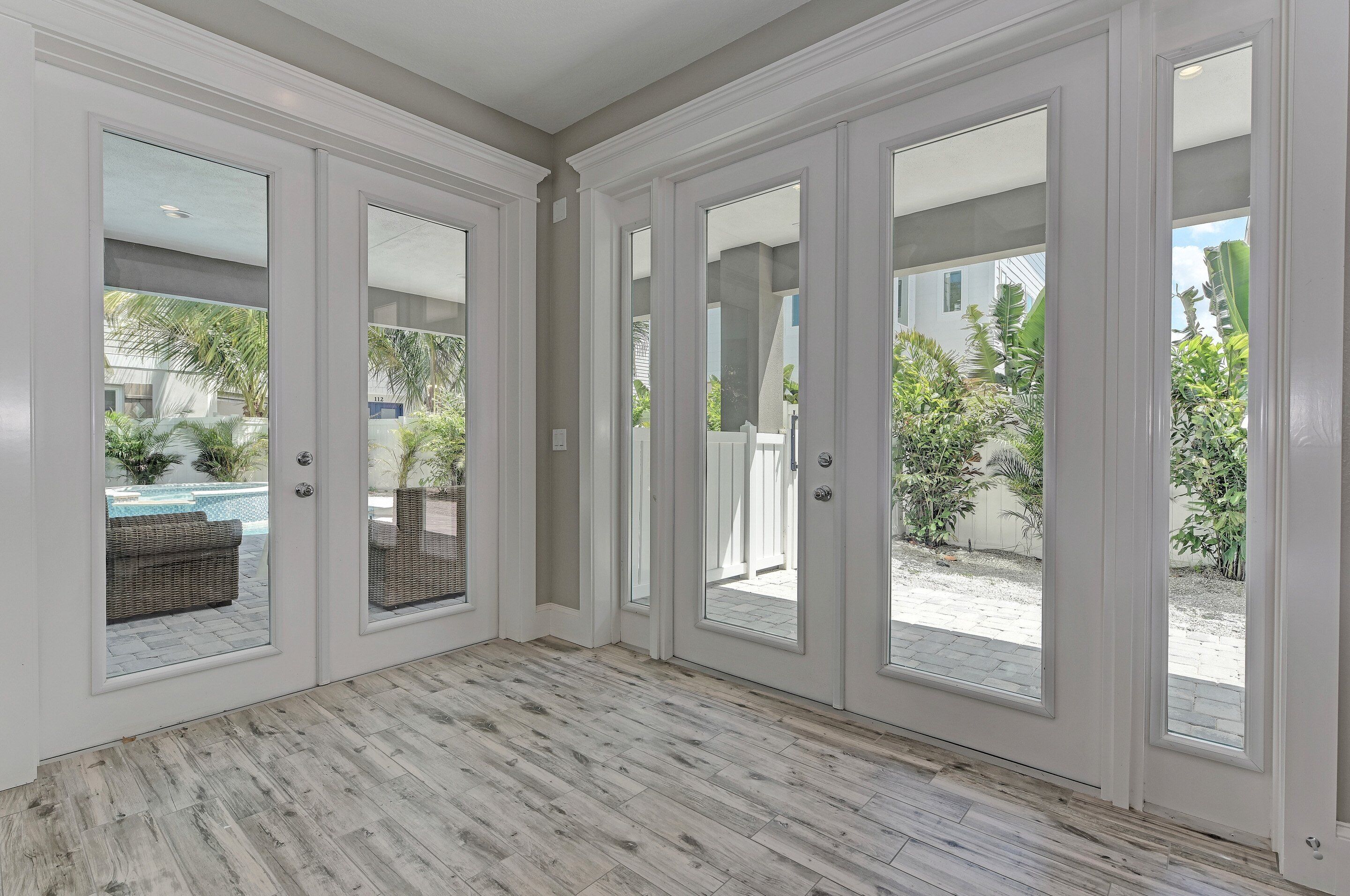 A spacious room with large sliding glass doors leading to a patio with a pool and outdoor furniture.