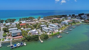An aerial view of a coastal residential area with houses, a marina, and clear blue waters.
