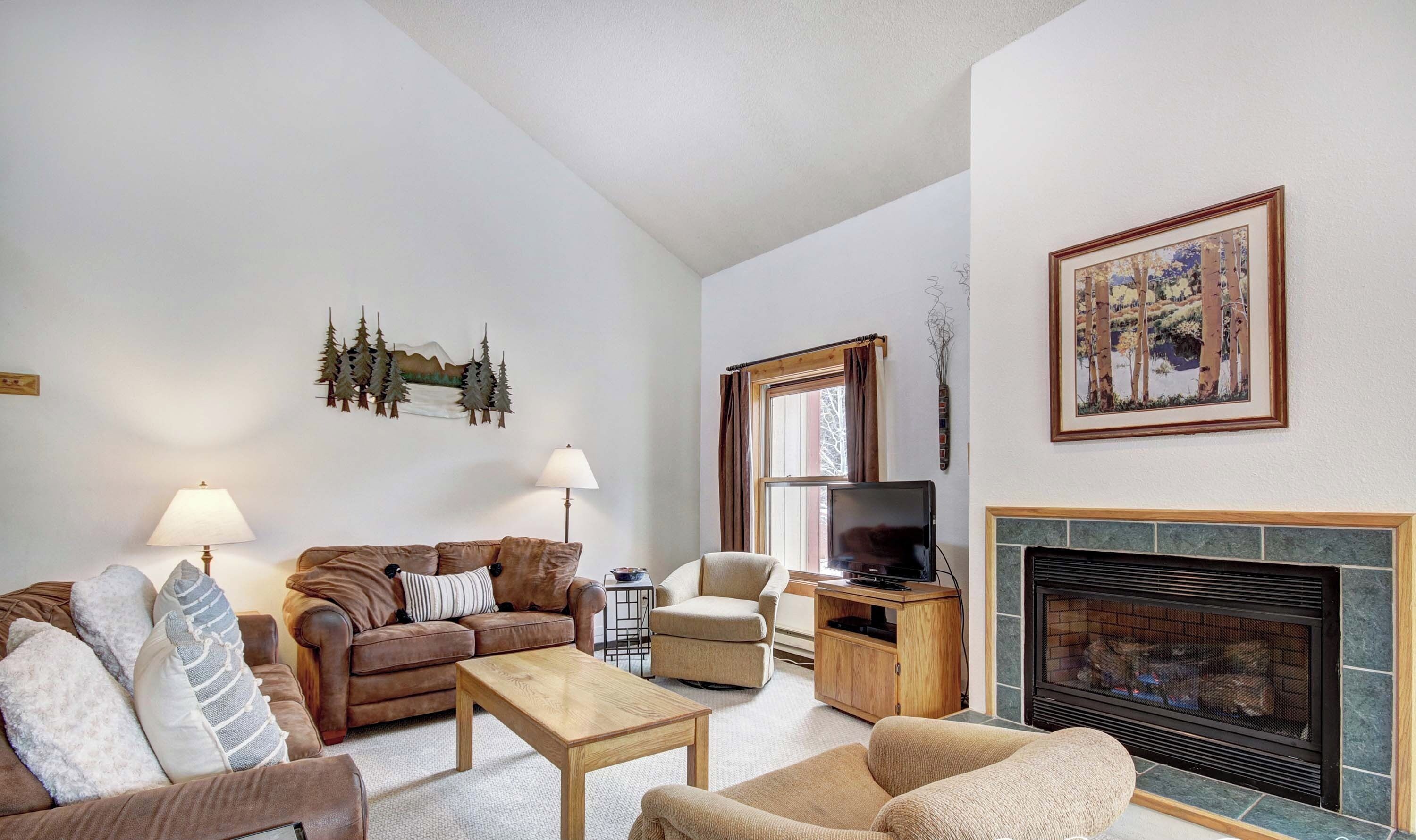 A living room with a fireplace, a sofa, a coffee table, and a television.