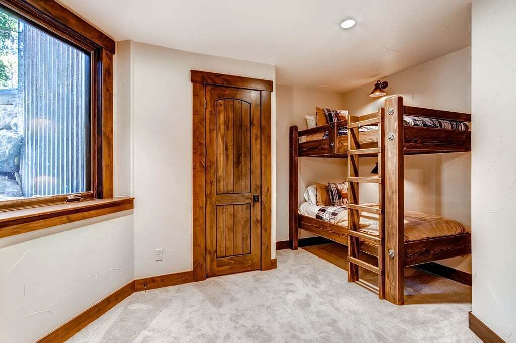 A room with a bunk bed, a wooden door, and a window with blinds.