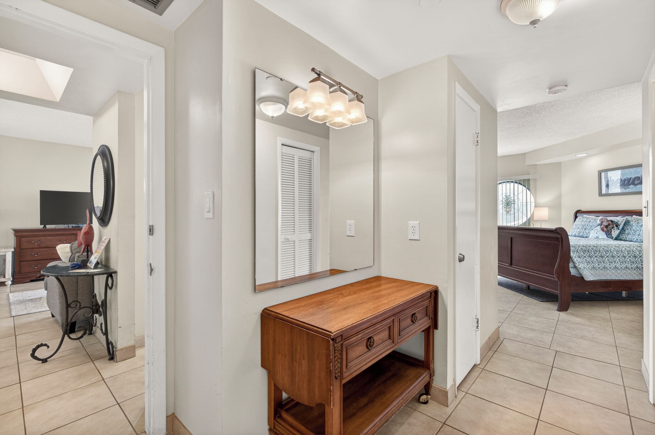 A bedroom with a bed, a bedside table, and a mirror.