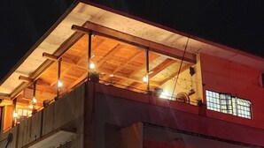 A building with a wooden balcony and a red wall. - We Travel Hostel (Moshi)