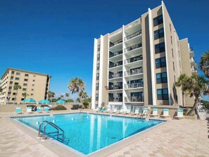 Um hotel com piscina, vƔrios andares e varandas.