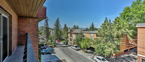 Una calle residencial con coches aparcados, cielo azul despejado y casas con fachadas de ladrillo.