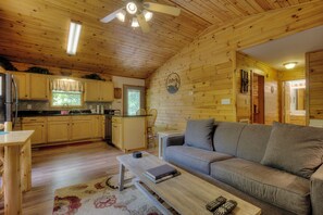 A wooden cabin interior with a kitchen, dining area, and living room.