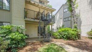 A two-story building with a central staircase, a balcony on the upper floor, and a well-maintained garden area.