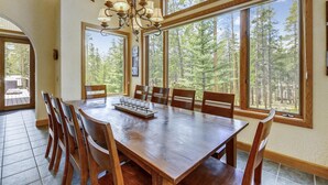 Un espace repas comprenant une grande table en bois, six chaises et un lustre.
