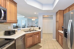 Une cuisine moderne avec des meubles en bois, des appareils électroménagers en acier inoxydable et un sol carrelé.