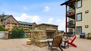 An outdoor patio with a stone fireplace, seating, and a grill. - SKI IN SKI OUT | Fraser Crossing 3517 | Base Area Bliss | Convenient Location (Winter Park)