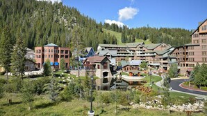 A resort with multiple buildings, a central courtyard, and a mountain backdrop. - SKI IN SKI OUT | Fraser Crossing 3517 | Base Area Bliss | Convenient Location (Winter Park)