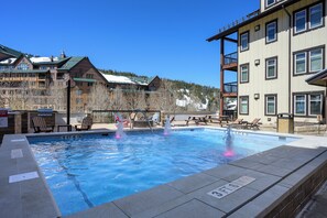 Relax by the pool surrounded by modern buildings with balconies and enjoy the scenic mountain views.