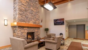 A cozy living area with a stone fireplace, comfortable seating, and a view of the outside. - SKI IN SKI OUT | Fraser Crossing 3517 | Base Area Bliss | Convenient Location (Winter Park)