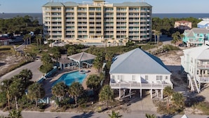 Un hotel grande con varios pisos, piscina y una casa de playa.