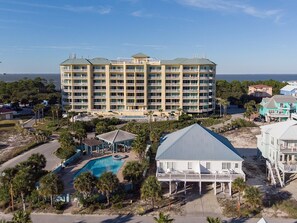 A large hotel with multiple floors, a swimming pool, and a beach house.