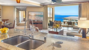 Une chambre d’hôtel moderne dotée d’un coin cuisine, d’un espace repas et d’un balcon offrant une vue sur la mer.