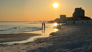 A beach with a sunset, people walking, and buildings in the background. - Bay View,  Villa Golf Cart, Private Deck, Blue Bayou 270 Fairways (Miramar Beach)