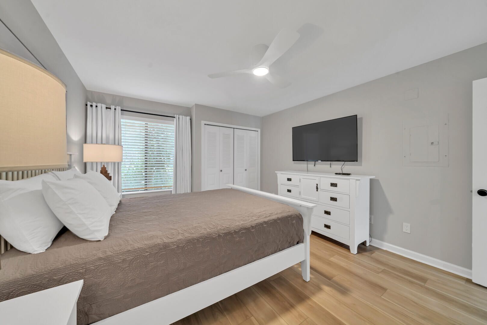 Une chambre à coucher avec un lit, une télévision, une armoire et un ventilateur de plafond.
