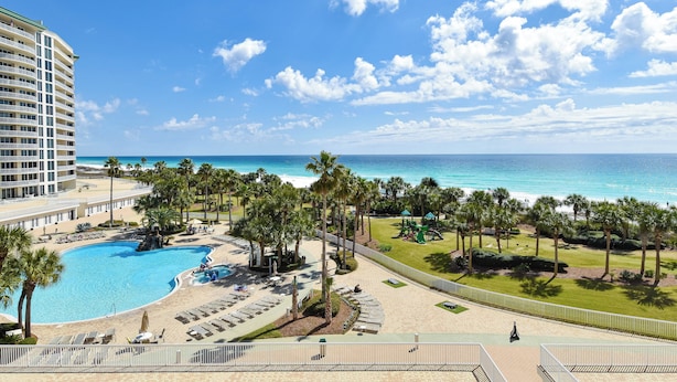 Ein Resort mit großem Pool, Palmen und Blick auf den Ozean.