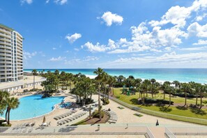A resort with a large pool, palm trees, and a view of the ocean.