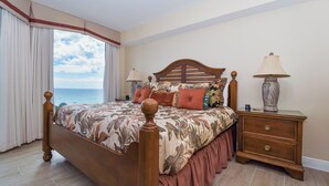 Ein Schlafzimmer mit einem großen Bett, einem Nachttisch und Blick auf den Ozean.