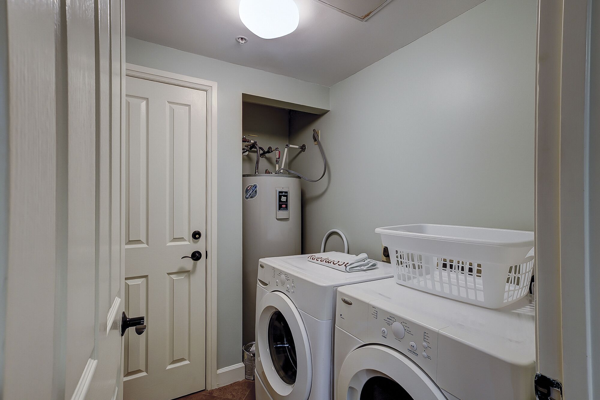 A laundry room with two front-loading washing machines, a dryer, and a utility sink.