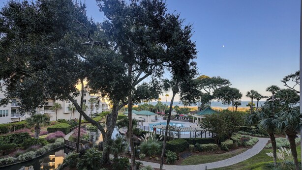 Ein Resort mit Swimmingpool, üppiger Bepflanzung und Meerblick.