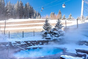 A snow-covered outdoor area with a hot spring, a ski lift, and a brick wall. - ☀ Sunny Base Area Condo | Zephyr Mountain Lodge 1303 | Convenient Location | Direct Slope Views! (Winter Park)