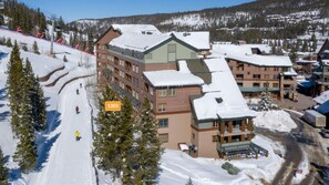 A multi-story hotel with a ski slope in the background. - ☀ Sunny Base Area Condo | Zephyr Mountain Lodge 1303 | Convenient Location | Direct Slope Views! (Winter Park)
