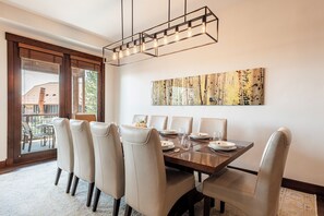 Un coin repas avec une table en bois, six chaises et un luminaire moderne.