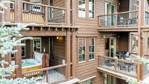 Une cabane en bois à plusieurs niveaux, dotée de balcons, d’un bain à remous et d’un espace salon extérieur.