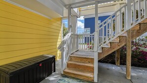 A wooden staircase leading to a porch with a black bench and a white railing. - A Wave from it All - Five Bedroom, Four Bath Beach House (Surfside Beach)