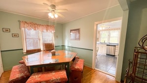 A dining area with a wooden table and benches, a ceiling fan, and a view into the kitchen. - Piece of Paradise-Pet Friendly-Walk to restaurants&shopping. (Cape May)