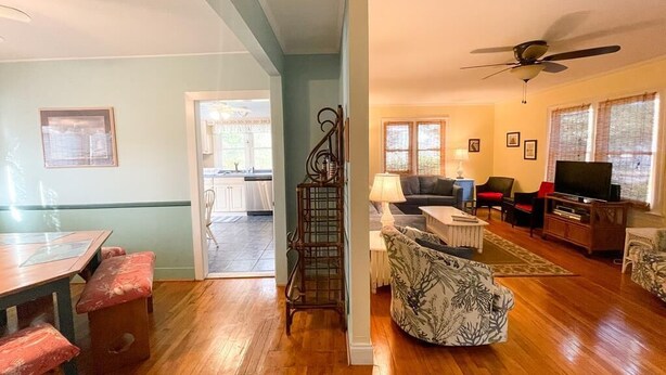 A spacious living room with a wooden floor, a ceiling fan, a television, and a dining area with a table and chairs. - Piece of Paradise-Pet Friendly-Walk to restaurants&shopping. (Cape May)