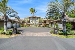 Um conjunto residencial com várias casas de dois andares, um caminho central e palmeiras.