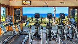 A gym with treadmills and elliptical machines, overlooking a scenic ocean view. - 🏖️Oceanfront Hali'i Kai Penthouse | 3BR Sunset Views (Waikoloa)