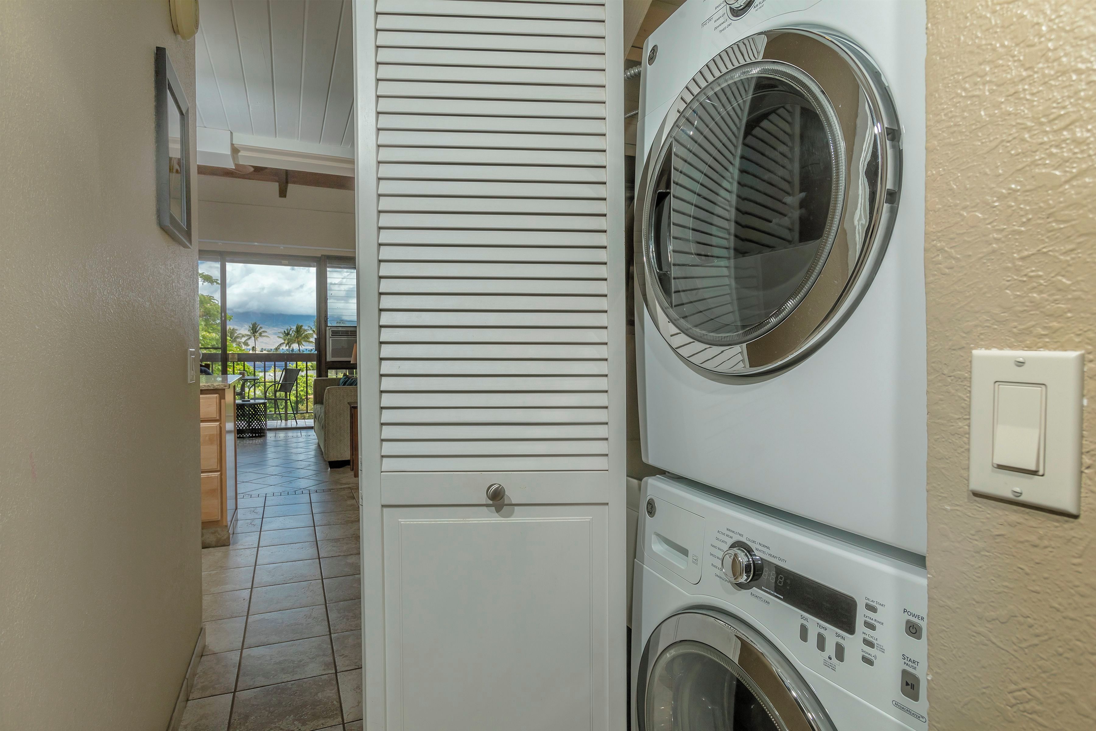 A laundry room with a washing machine and dryer, a door leading to a balcony with outdoor furniture, and a tiled floor.