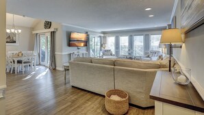 Ein modernes Wohnzimmer mit Sofa, Fernseher und Essbereich mit Tisch und Stühlen.