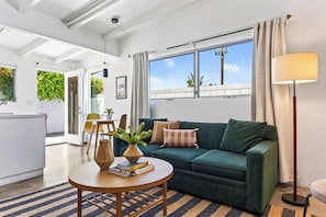 A modern living room with a green sofa, a round wooden coffee table, and a floor lamp.
